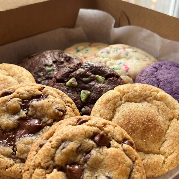 Assorted cookies, including chocolate chip, snickerdoodle, mint chocolate, and purple, in a box.